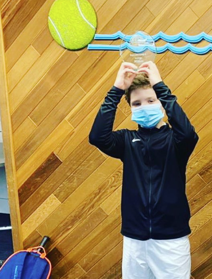 Luca Q. with championship trophy — NMBA junior tennis success story